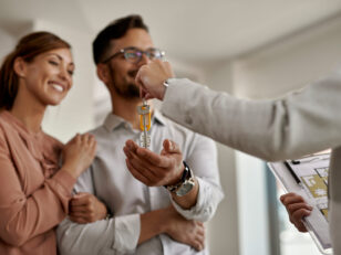 Close-up of real estate agent giving new house keys to a couple.